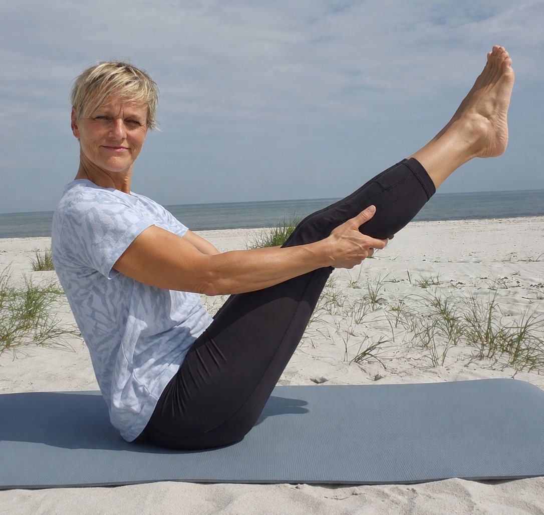 Angela Gutting bei einer Pilatesübung im Schwebesitz am Strand